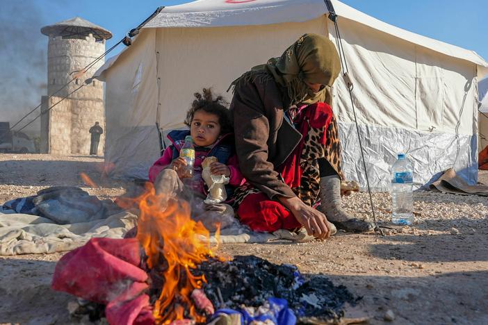 Syrians warm up by a fire at a make-shift shelter for people who were left homeless, near the rebel-held town of Jindayris on Feb. 8, 2023.