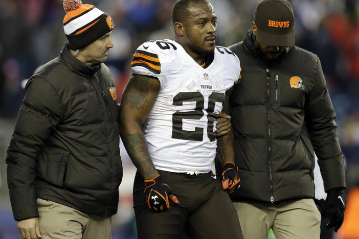 Cleveland Browns running back Willis McGahee is helped from the field after getting injured during an NFL game against the New England Patriots on Dec. 8, 2013. Ten retired NFL players, including McGahee, accused the league of lies, bad faith and flagrant violations of federal law in denying disability benefits in a potential class action lawsuit filed on Thursday in Baltimore.
