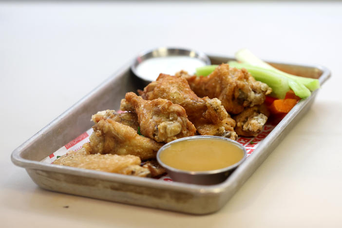 An order of Buffalo chicken wings sits on a counter at a restaurant in San Francisco on Feb. 11, 2022. Party trays of frozen chicken wings are cheaper than last year, according to the USDA. The National Chicken Council expects Americans to gobble up 1.45 billion wings this weekend.