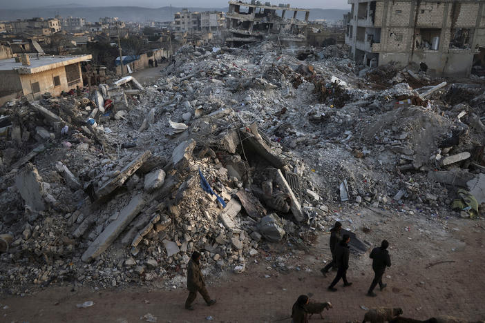 People walk past collapsed buildings on Thursday in the town of Jinderis, in Syria's Aleppo province, days after a massive earthquake devastated the region.