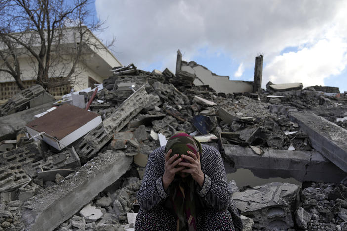A woman sits on the rubble as emergency rescue teams search for people under the remains of destroyed buildings in Nurdagi town on the outskirts of Osmaniye city southern Turkey, on Feb. 7. Now, nearly a week later, many people in Osmaniye are still living in tents and other makeshift shelters.