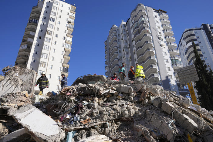 Emergency teams search for people in the rubble of a destroyed building in Adana, southern Turkey, Tuesday, Feb. 7, 2023. For Syrians and Ukrainians fleeing the violence back home, the earthquake that struck in Turkey and Syria is but the latest tragedy.