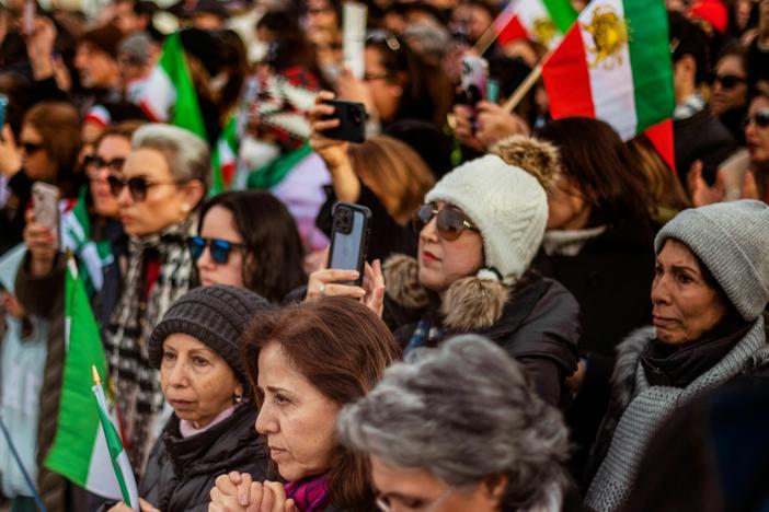 People listen to a speaker during a demonstration to denounce the Iranian government and express support with anti-government protesters in Iran, in Washington, DC.