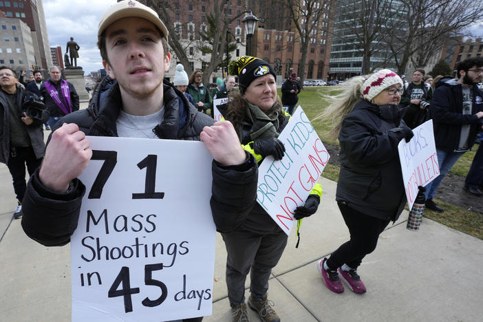 Austin Hunt holds a sign with current and former Michigan State University students during a rally at the state Capitol in Lansing, Mich., Wed., Feb. 15, 2023, after a gunman opened fire on the Michigan State University campus Monday night.