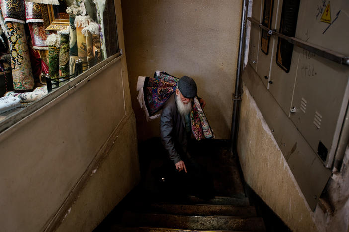 Inside the Grand Bazaar, a trader carries a carpet from Qom, which is known for its silk carpets.