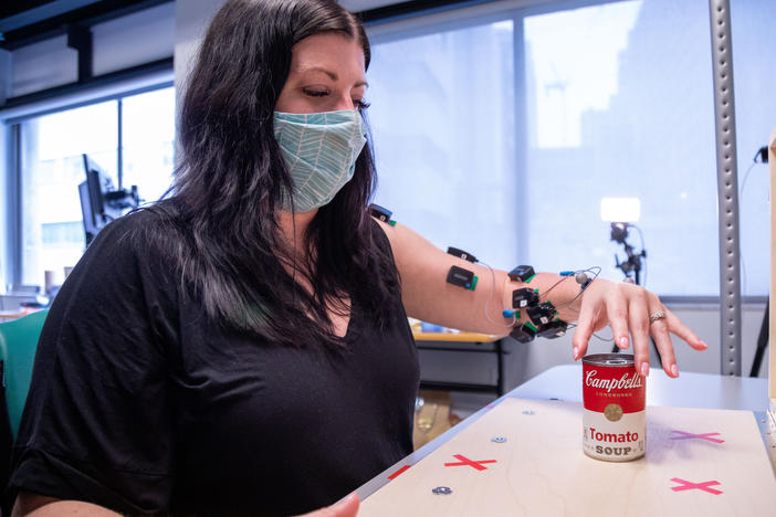 Research participant Heather Rendulic prepares to grasp and move a can of tomato soup at Rehab Neural Engineering Labs at the University of Pittsburgh.