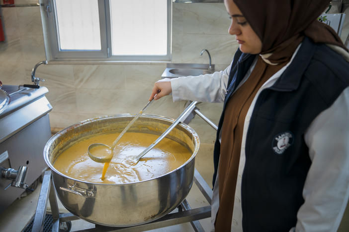 A woman tends to lentil soup at a municipal soup kitchen in Gaziantep, Turkey. On the first day after the quake, the kitchen's director says they distributed soup to more than 200,000 people.