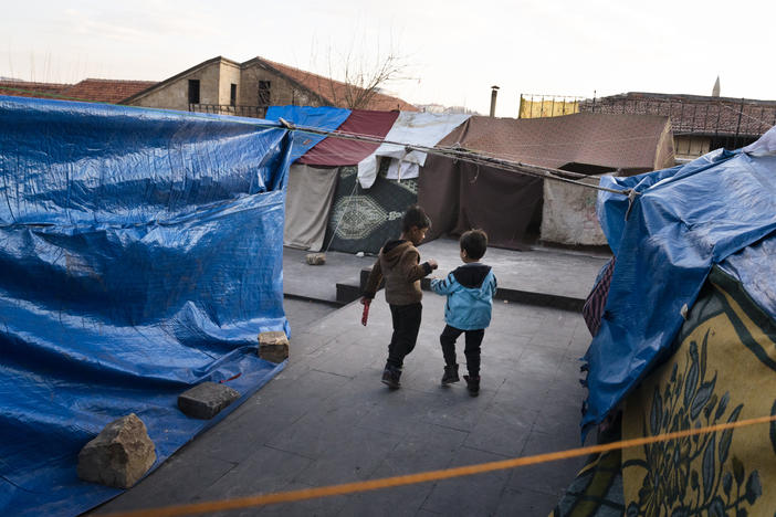 Two boys walk through a small tent encampment in Gaziantep, Turkey, on Thursday, Feb. 16. People have set up makeshift tents since they are too afraid to return to their homes after the earthquake.