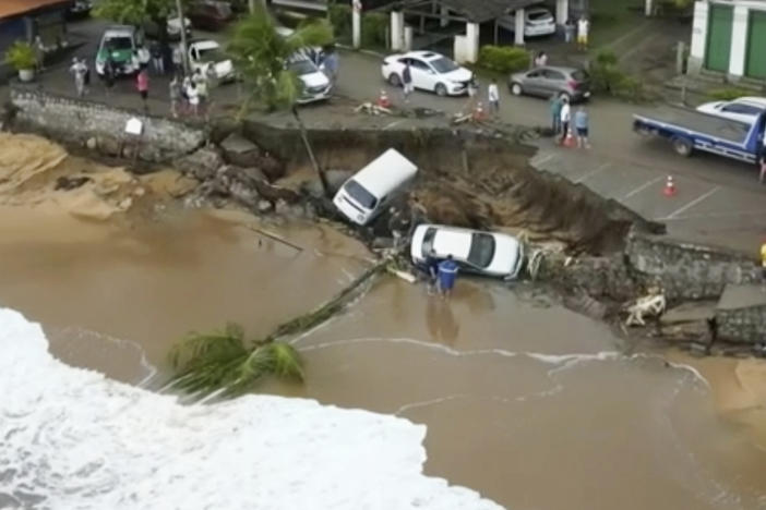 This photo provided by the Sao Paulo Government shows vehicles fallen from an elevated area along the beach in Sao Sebastiao, east of Sao Paulo, Brazil, Sunday, Feb. 19, 2023, after it was damaged by a severe weather system went through the area.