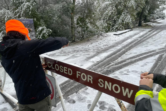 A parks worker puts up a closed sign at the entrance to Mount Tamalpais State Park in Mill Valley, Calif., on Friday. California and other parts of the West are facing heavy snow and rain from the latest winter storm to pound the United States. The National Weather Service has issued blizzard warnings for the Sierra Nevada and Southern California mountains.