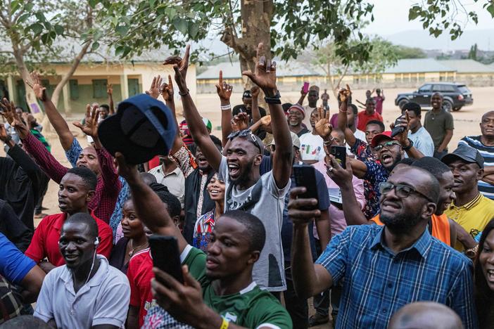 People cheer as ballot papers are counted at a polling station in Abuja at the end of election day in Nigeria