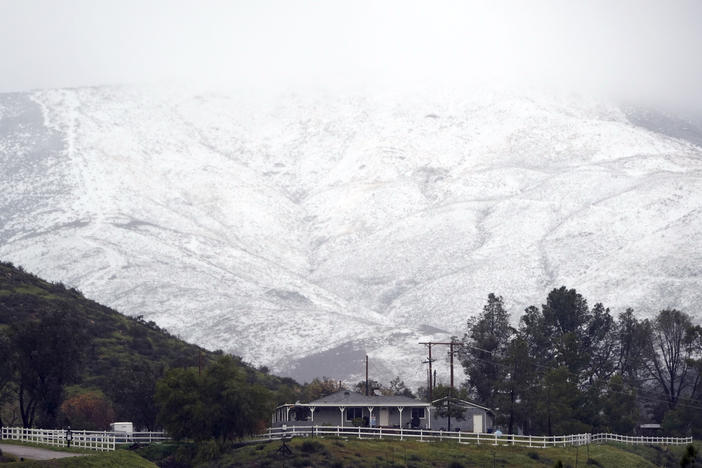 Snow accumulates on a hillside over a property Friday, Feb. 24, 2023, in Agua Dulce, Calif. California and other parts of the West faced heavy snow and rain Friday from the latest winter storm to pound the U.S.