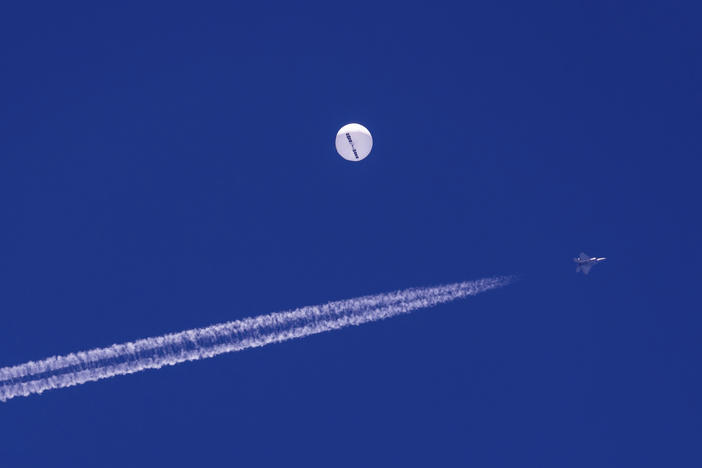 A fighter jet flies near a large balloon drifting above the Atlantic Ocean, just off the coast of South Carolina near Myrtle Beach, Feb. 4. Minutes later, the balloon was struck by a missile from an F-22 fighter jet, ending its weeklong traverse over the United States. China said the balloon was a weather research vessel blown off course, a claim rejected by U.S. officials.