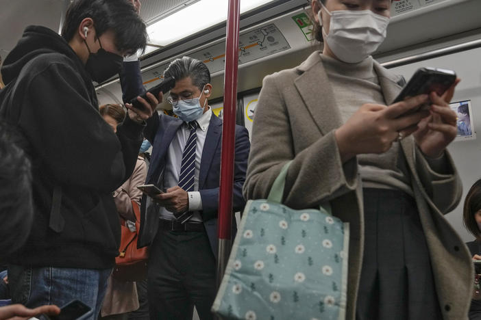 Commuters wearing face masks browse their smartphones as they ride on a subway train in Hong Kong on Feb. 7, 2023. Hong Kong will lift its mask mandate Wednesday, March 1, 2023, ending the city's last major restriction imposed during the COVID-19 pandemic.