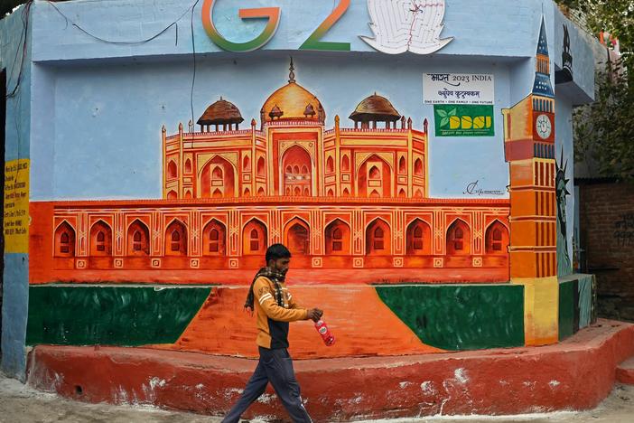 A man walks past a wall mural of Humayun's Tomb under the logo of the Group of 20 summit, in New Delhi on Jan. 4.