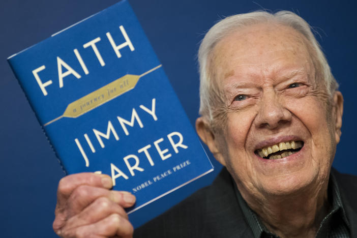 Former U.S. President Jimmy Carter holds up a copy of his book <em>Faith: A Journey For All</em> at a book signing event at Barnes & Noble bookstore on March 26, 2018.