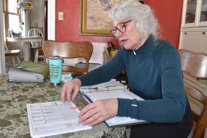 Jennifer Mitchell thumbs through her husband's medical records from his time at the Montana State Hospital. Records show doctors took Mitchell's husband off some of his congestive heart failure medications. Mitchell says she was never consulted.