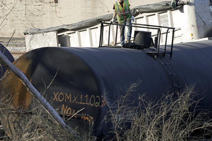 A cleanup worker stands on a derailed tank car of a Norfolk Southern freight train in East Palestine, Ohio, continues, Feb. 15, 2023.