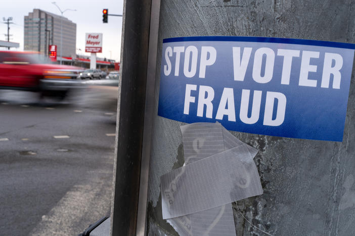 A sticker on a lamp post warns of voter fraud on Nov. 7, 2022, in Anchorage, Alaska. Alaska is part of a bipartisan compact of more than 30 states that shares voting data.