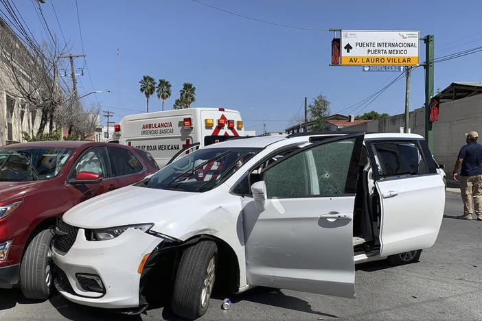 A member of the Mexican security forces stands next to a white minivan with North Carolina plates and several bullet holes at the scene of the crime in Matamoros on Friday.