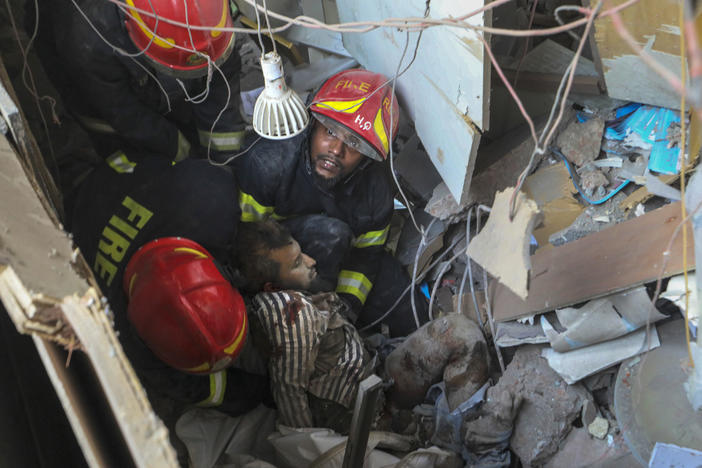 Fire officials rescue an injured person from the debris of a commercial building after an explosion, in Dhaka, Bangladesh, Tuesday.