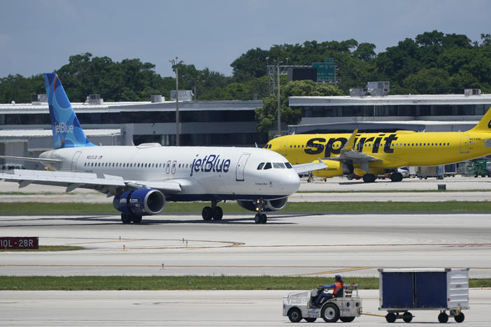 A JetBlue Airways Airbus A320 (left) passes a Spirit Airlines Airbus A320 as it taxis on the runway on July 7, 2022, at the Fort Lauderdale-Hollywood International Airport in Fort Lauderdale, Fla. The Biden administration wants to block JetBlue from buying Spirit, saying the deal would reduce competition and hurt travelers.