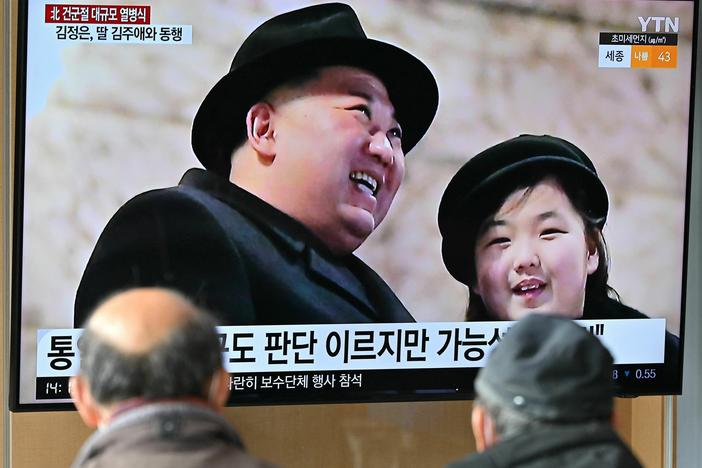 People watch a television screen showing a news broadcast with an image of North Korean leader Kim Jong Un, left, and his daughter presumed to be named Ju Ae attending a military parade held in Pyongyang to mark the 75th founding anniversary of its armed forces, at a railway station in Seoul on Feb. 9, 2023.