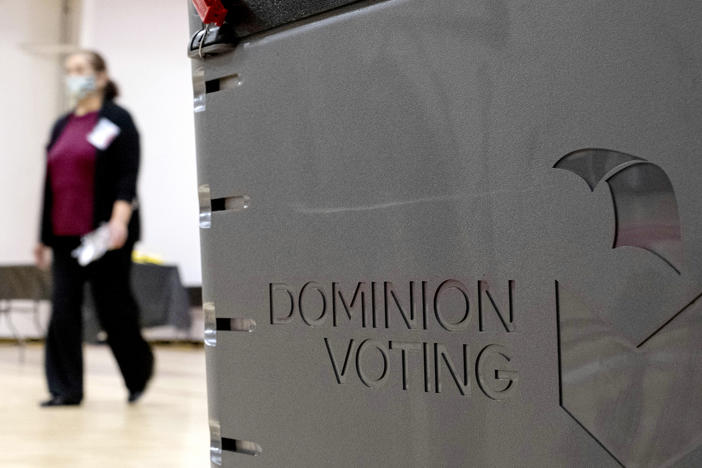 In this 2021 file photo, a Georgia poll worker passes a Dominion Voting Systems ballot scanner. Dominion, which has been the subject of conspiracy theories since the 2020 election, was recently ditched by officials in California's Shasta County.