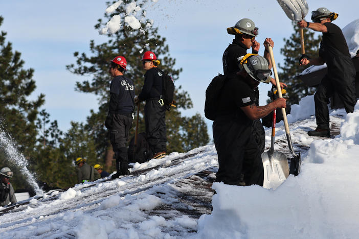 Members of the California Army National Guard Joint Task Force Rattlesnake shovel snow from a rooftop after a series of winter storms dropped more than 100 inches of snow in the San Bernardino Mountains in Southern California on March 8, 2023 in Crestline, California.