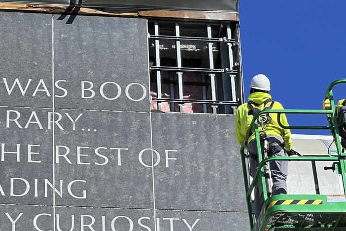 Workers remove a partial quote by Malcolm X from the facade of the main library at the University of Rhode Island in Kingston, R.I..