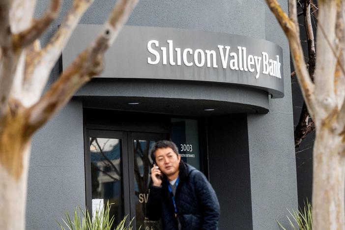 A pedestrian speaks on a mobile telephone as he walks past Silicon Valley Bank's headquarters in Santa Clara, Calif., on Friday after a run on deposits made it no longer tenable for the bank to stay afloat on its own.