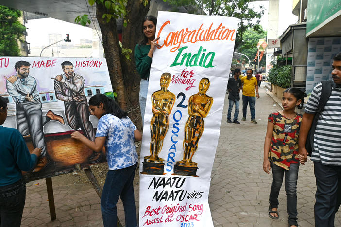 Art school students in Mumbai finish up a painting of Indian actors N.T. Rama Rao Jr. (left) and Ram Charan of the movie <em>RRR</em>, whose dance song "Naatu Naatu" became the first song from an Indian film to win an Oscar.