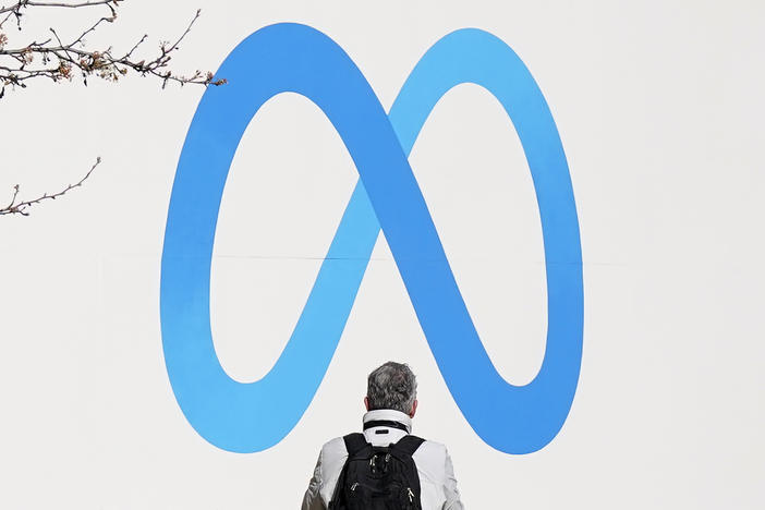 A person stands in front of a Meta sign outside of the company's headquarters in Menlo Park, Calif. on March 7.