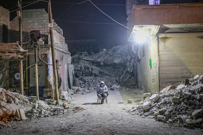 A quake survivor spends a night outside in Idlib, Syria on Feb. 9, 2023, following 7.7 and 7.6 magnitude earthquakes centered in neighboring Turkey. A doctor in Syria says it's still difficult to get needed medical supplies.