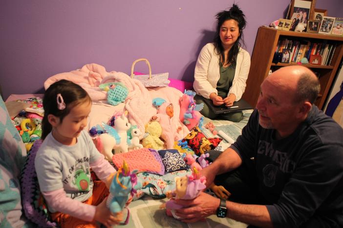 Former state lawmaker Kay Bounkeua takes a break from her work as her daughter Ryla Bounkeua plays with Kay's stepdad Jeffrey Strong in Rio Rancho, N.M, March 13.