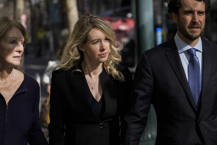 Former Theranos CEO Elizabeth Holmes, center, walks into court in San Jose, Calif., on Friday alongside her mother, Noel Holmes, and partner, Billy Evans.