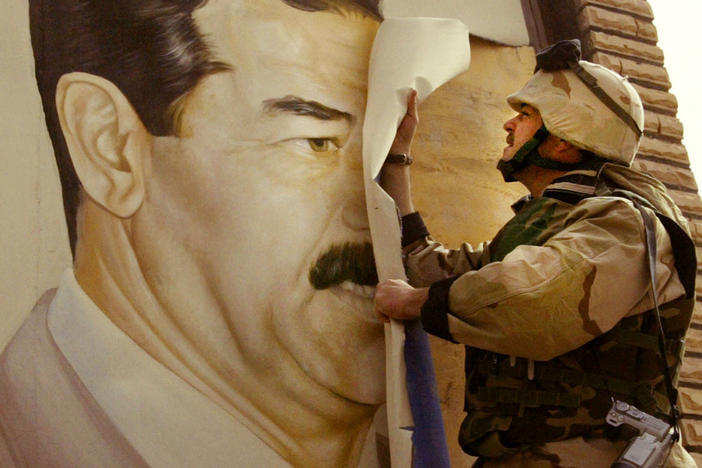 U.S. Marine Maj. Bull Gurfein pulls down a poster of Iraqi President Saddam Hussein on March 21, 2003, a day after the start of the U.S. invasion, in Safwan, Iraq.