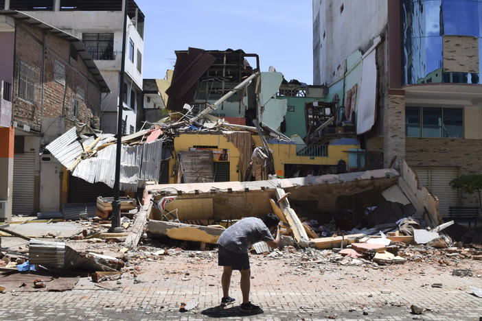 A man takes a photo of a building that collapsed after an earthquake shook Machala, Ecuador, on Saturday.