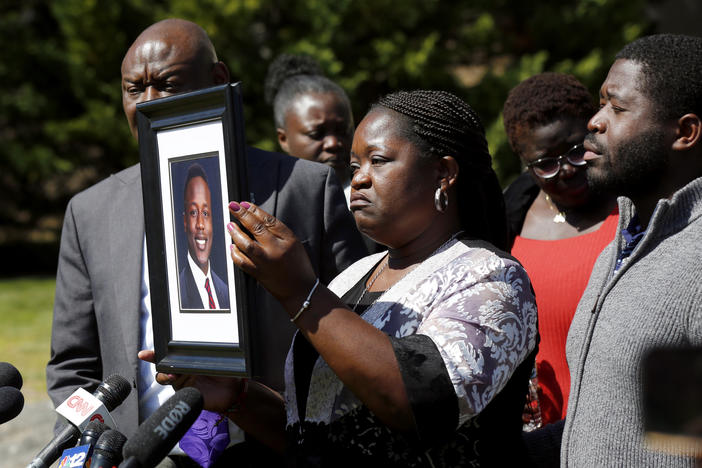 Caroline Ouko holds a portrait of her son, Irvo Otieno, as attorney Ben Crump (left) and her older son, Leon Ochieng (right) look on at the Dinwiddie Courthouse in Dinwiddie, Va., on Thursday.
