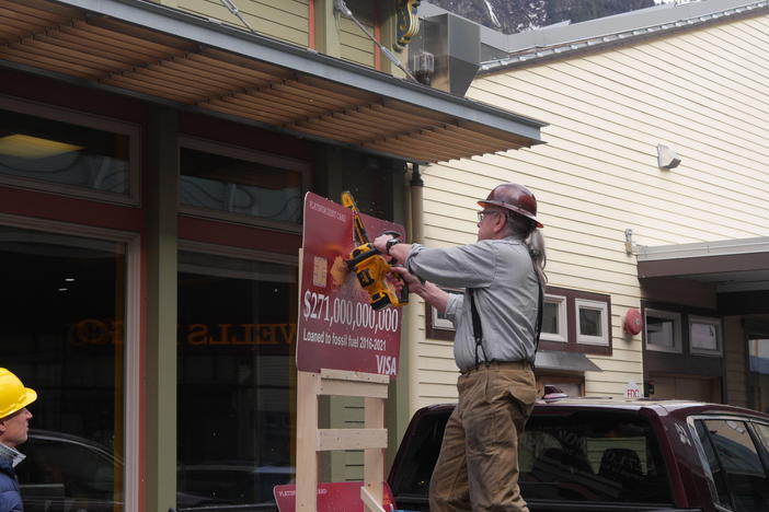 Bob Schroeder, an organizer with 350Juneau, sawed credit card replicas in half outside a Wells Fargo branch in Juneau, Alaska.