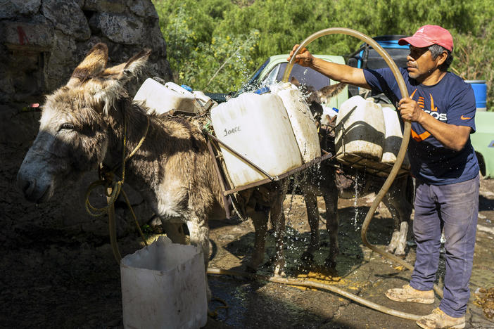 A man fills cans with water in order to bring water to homes in Xochimilco, Mexico.