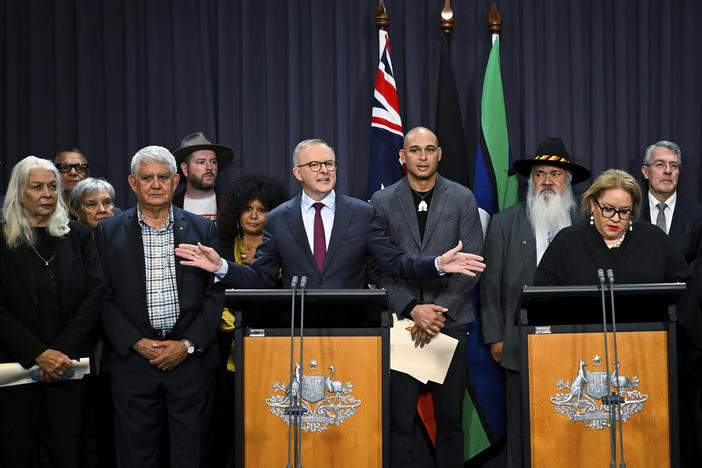 Australian Prime Minister Anthony Albanese, at the left podium, is surrounded by members of the First Nations Referendum Working Group as he speaks during a press conference at Parliament House in Canberra, Thursday, March 23, 2023.