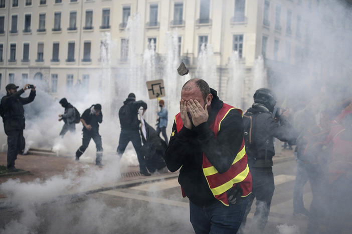 Protesters run amid the tear gas during a demonstration in Lyon, central France, Thursday, March 23, 2023. French unions are holding their first mass demonstrations Thursday since President Emmanuel Macron enflamed public anger by forcing a higher retirement age through parliament without a vote.