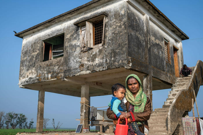 Kelna Begum, 30, stands with her child in front of a building that's been raised to survive seasonal floods in her village of Golabari in the Sunamganj region of northern Bangladesh.
