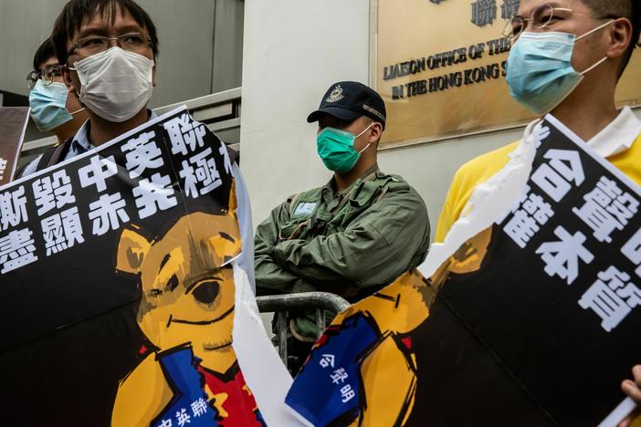 Pro-democracy activists tear a placard of Winnie-the-pooh that represents Chinese President Xi Jinping during a protest against a proposed new security law outside the Chinese Liaison Office in Hong Kong on May 24, 2020.