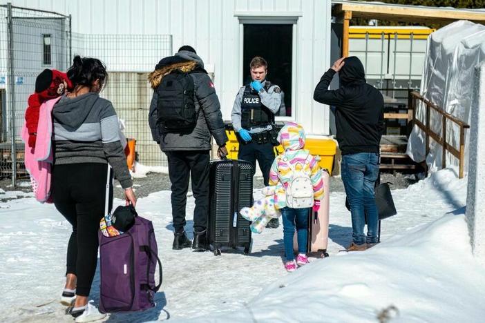 An officer speaks to migrants as they arrive at the Roxham Road border crossing in Quebec, Canada, earlier this month.