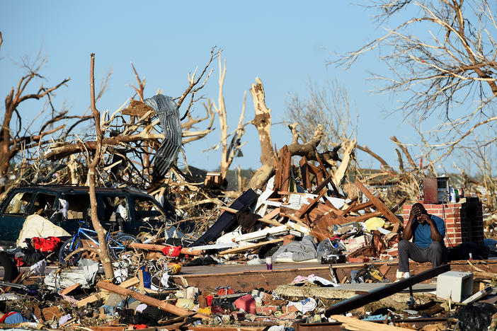A man sits among the wreckage caused by a series of powerful storms and at least one tornado on March 25, 2023 in Rolling Fork, Mississippi.