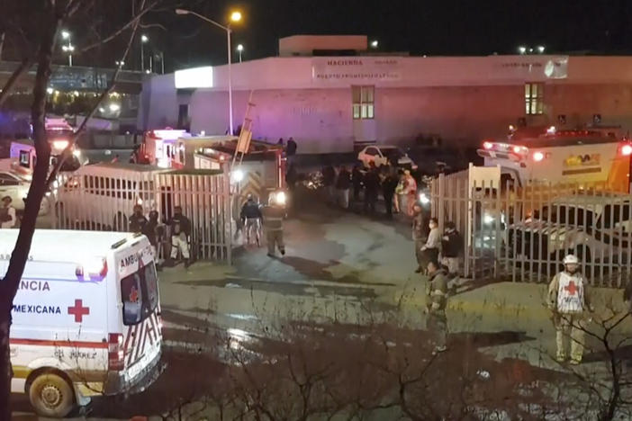 An image taken from a video shows ambulances and rescue team staffers outside an immigration center in Ciudad Juarez, Mexico, on Tuesday.