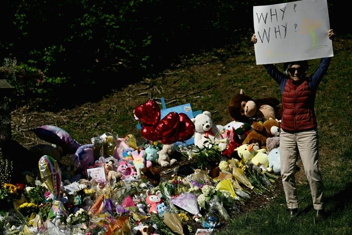 A mourner on Wednesday holds a sign reading "Why? Why?" at a makeshift memorial for victims of the shooting at the Covenant School in Nashville, Tennessee.