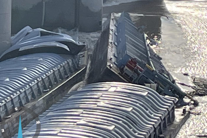 Three barges are jammed up against the McAlpine Dam on the Ohio River, just off the shore in Louisville, Ky. Officials say a barge carrying 1,400 tons of methanol is partially submerged.